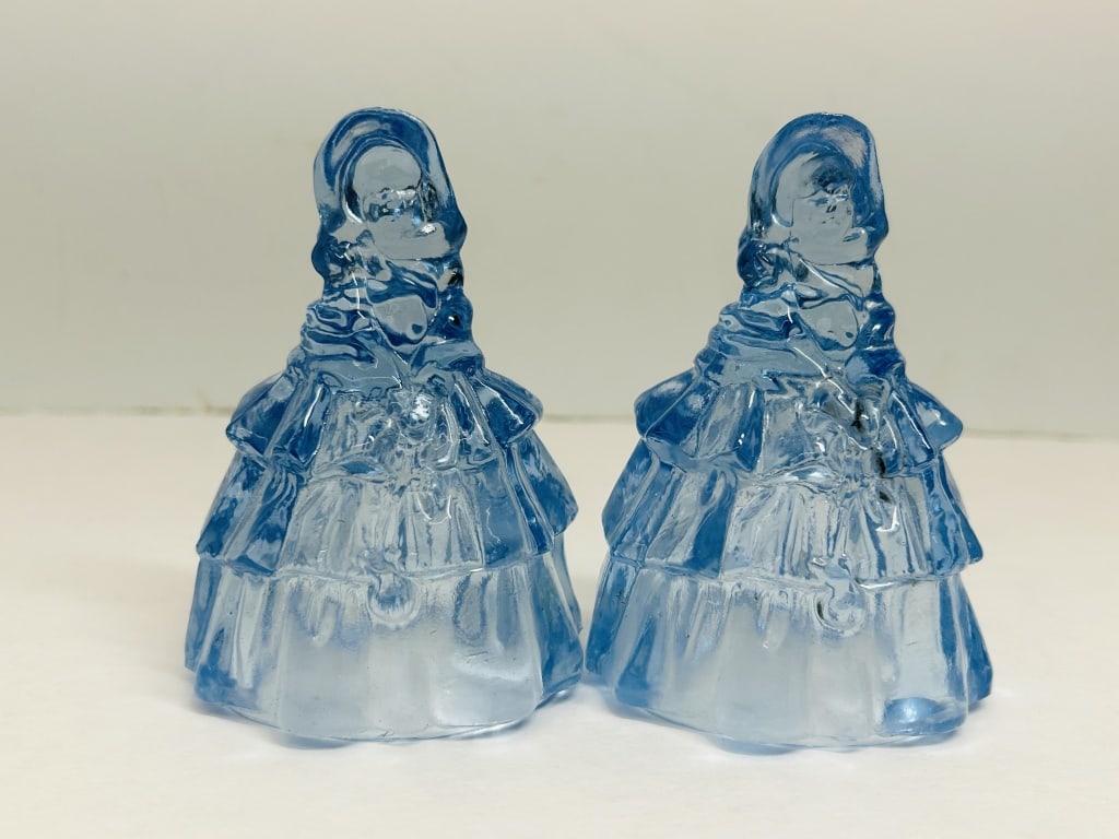 BOYD BLUE GLASS LOUISE FIGURINES, C.1980: A pair of pressed blue glass Miss Elizabeth figurines manufactured by Boyd?s Crystal Art Glass. Each figure features a B in a diamond trademark embossed on the reverse of the skirt.