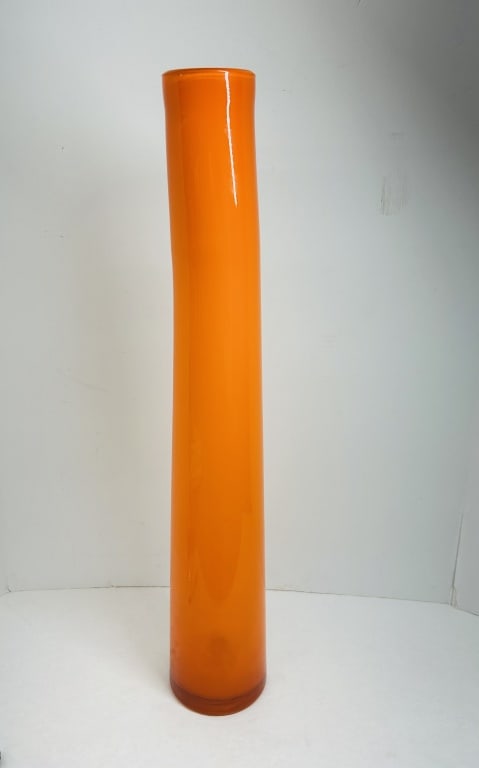 ORANGE CASED ART GLASS VASE, CIRCA 1970: Hand-blown chimney vase featuring vibrant orange cased glass over an opaque white interior. The mid-century modern form displays a slight organic curve and a fire-polished rim.
