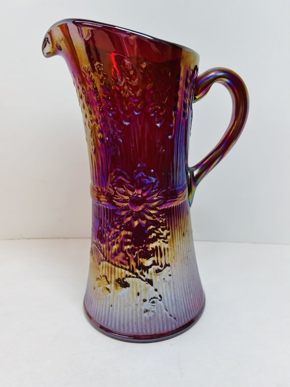 L.G. WRIGHT RED CARNIVAL GLASS PITCHER: L.G. Wright carnival glass water pitcher in the Field Flower pattern, featuring a ruby red body with a multi-colored iridescent finish. The base is impressed with the circular LGW trademark.