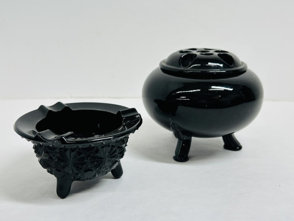 L.E. SMITH BLACK AMETHYST GLASS SET, MID-20TH CENTURY: A two-piece collection of black amethyst glass by L.E. Smith, consisting of a footed rose bowl with a matching thirteen-perforation flower frog lid and a footed ashtray featuring a pressed geometric p