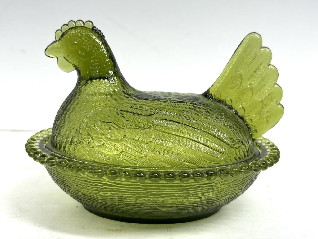 INDIANA GLASS OLIVE GREEN HEN ON NEST: Two-piece pressed glass hen on a nest dish manufactured by Indiana Glass Company. The olive green vessel features a detailed nesting hen lid and a basketweave base with a beaded rim.