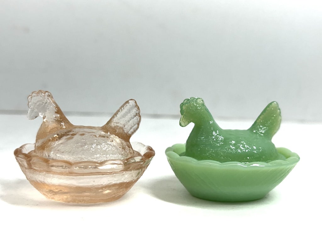 PRESSED GLASS HEN ON NEST SALTS, CIRCA 1950: A pair of two-piece miniature covered dishes in the form of nesting hens, likely intended for use as individual salt cellars. One example is produced in translucent peach pressed glass with a stippled
