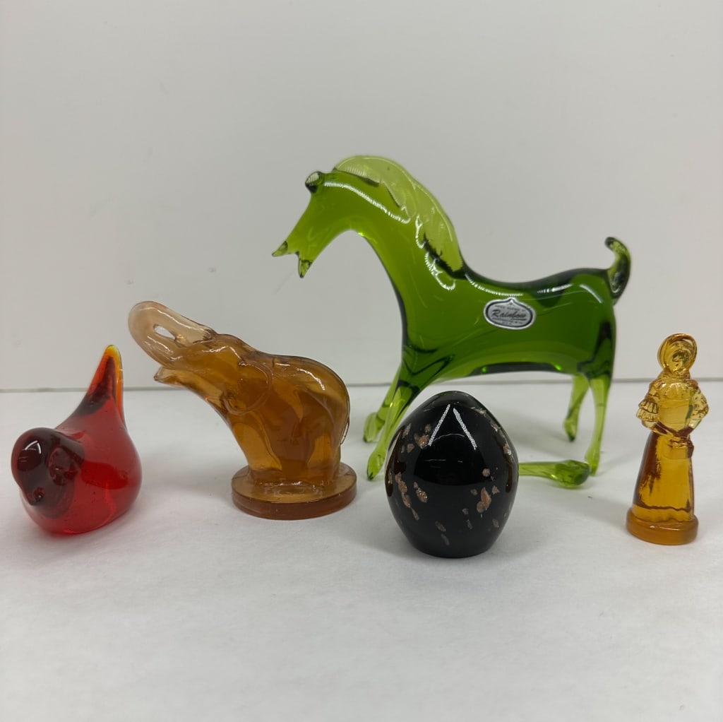 RAINBOW ART GLASS FIGURINE COLLECTION, MID-CENTURY: A collection of mid-century modern glass figurines featuring a hand-blown green horse produced by Rainbow Art Glass. The assortment includes assorted animal and human forms in amber, red, and