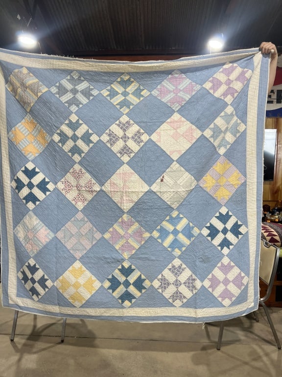 Two Vintage Hand-Stitched Cotton Quilts Including Bear Paw and Spool Patterns: This lot consists of two vintage, hand-stitched cotton quilts. The first quilt features a Bear Paw pattern, also known as Duck and Ducklings, consisting of twenty-five patterned blocks set on point