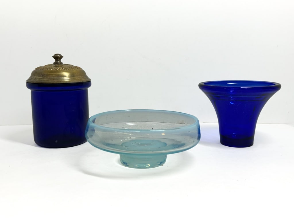 TIFFIN AND VINTAGE BLUE GLASS, 1930-1960: Tiffin cobalt blue flared vase with needle-etched scrolls and a black amethyst rim, signed on the interior wall, accompanied by an aqua opalescent pedestal bowl and a cobalt glass jar with a brass-ton