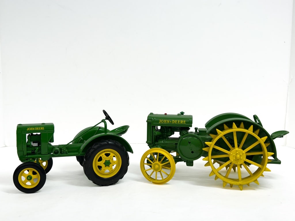 ERTL JOHN DEERE DIE-CAST TRACTORS, 1990S: A pair of 1/16 scale die-cast tractors manufactured by Ertl, featuring the John Deere Model D with steel lug wheels and the rubber-tired Model L. Both models display authentic manufacturer livery, ste