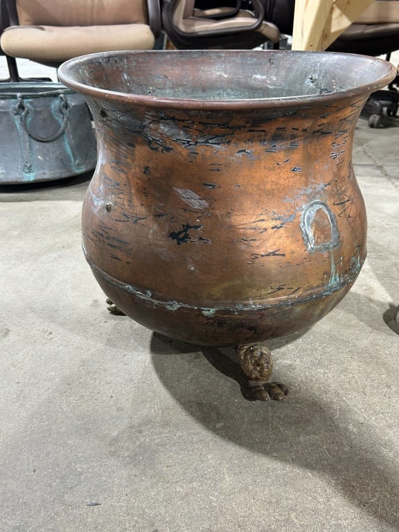 ENGLISH COPPER LOG BUCKET, 19TH CENTURY: Large wrought copper log bucket featuring a rolled rim and reinforced horizontal seam. The vessel is raised on three cast brass lion's paw feet secured with internal rivets.