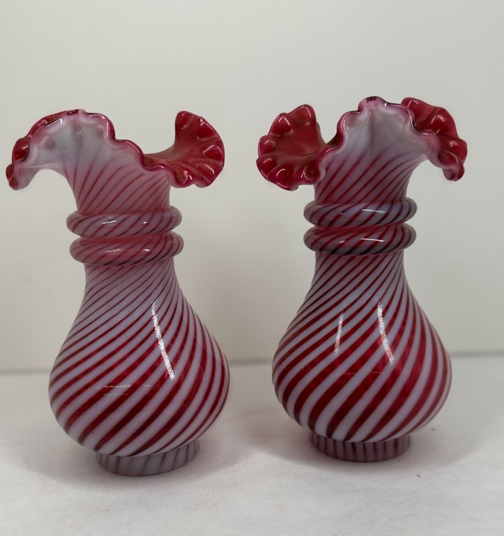 FENTON CRANBERRY OPALESCENT VASES, 20TH CENTURY: A pair of mold-blown cranberry opalescent glass vases produced by Fenton Art Glass in the Spiral Optic pattern. Each piece features a ribbed spiral swirl body, twin applied glass neck rings, and a han