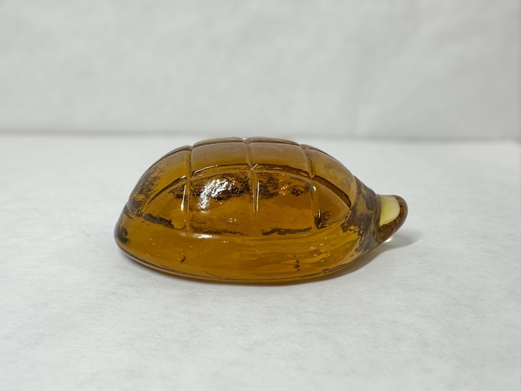 TWO GLASS ANIMAL FIGURINES: Two decorative glass animal figurines comprising an amber glass turtle and an iridescent blue collie. The turtle displays a molded grid shell and internal yellow-white base swirl, while the seated