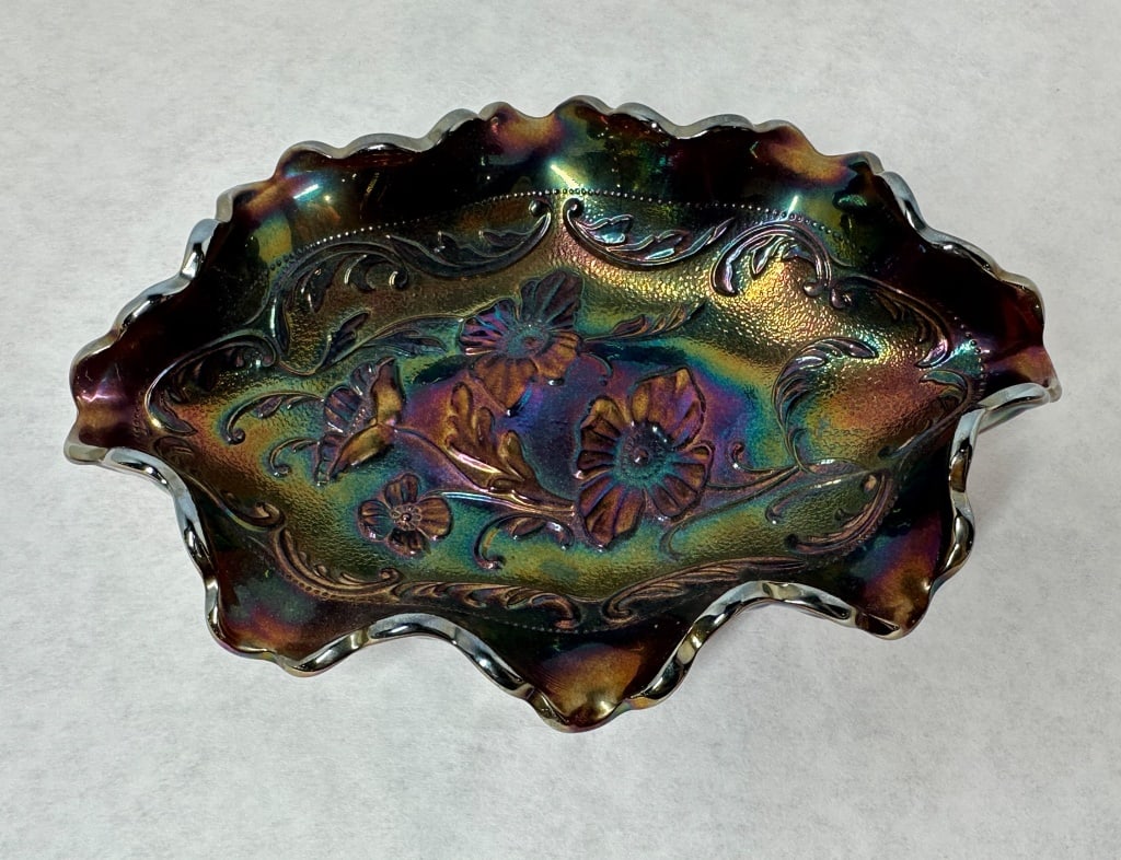 FENTON AMETHYST CARNIVAL GLASS BOWL, 1970S: A Fenton Art Glass Company ruffled oval bowl in amethyst carnival glass featuring the Poppy pattern. A molded script Fenton mark within an oval cartouche is centered in the starburst on the underside 