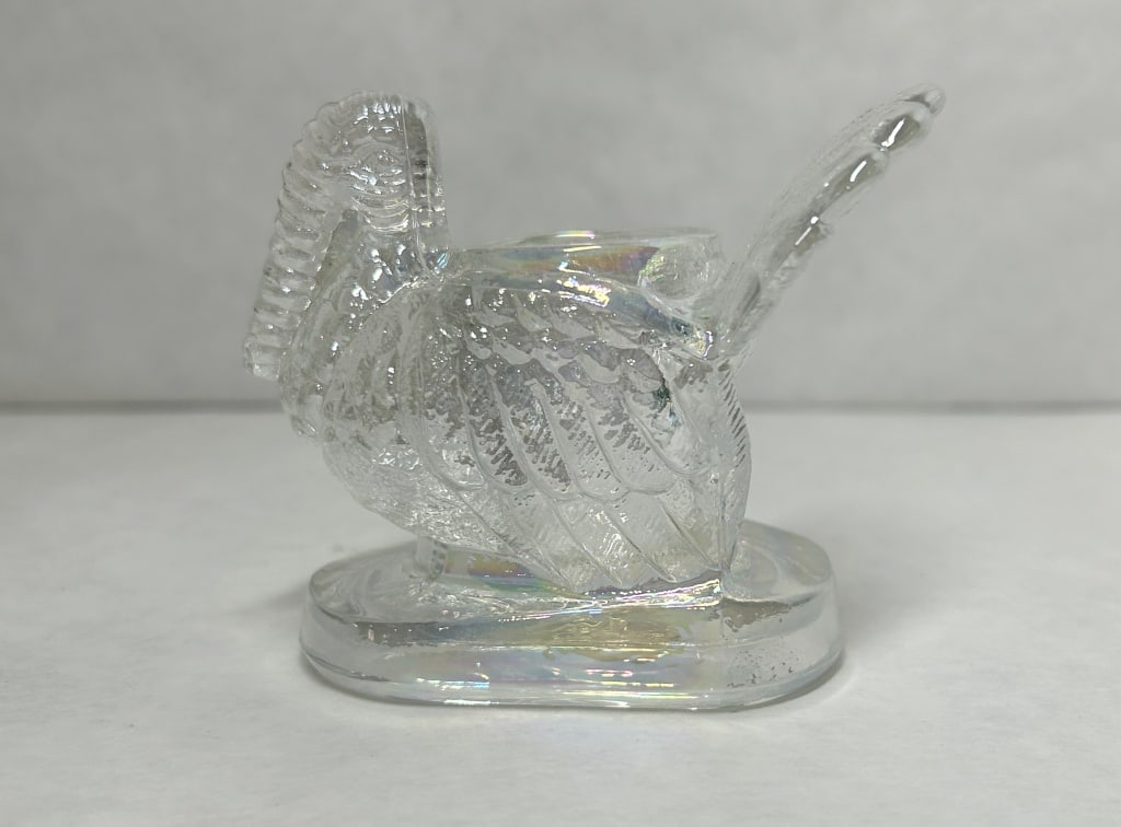 MOSSER IRIDESCENT GLASS TURKEY FIGURINE: Clear pressed glass turkey figurine featuring an iridescent finish and textured plumage. The body is hollowed to form a central cylindrical vessel.