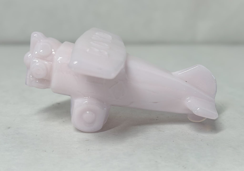 BOYD SLAG GLASS AIRPLANE, 20TH CENTURY: A miniature slag glass airplane produced by Boyd's Crystal Art Glass, modeled as a high-wing monoplane with a radial engine. The upper surface of the wing is embossed with the BOYD maker mark.