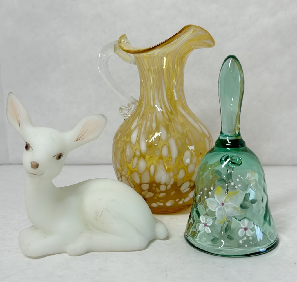 FENTON ART GLASS TRIO, 20TH CENTURY: A trio of decorative art glass items produced by the Fenton Art Glass Company. The lot includes a white satin reclining deer figurine signed Carol S with a gold foil label reading Authentic Fenton HAN