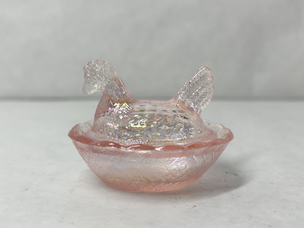 MINIATURE PINK IRIDESCENT GLASS HEN: A miniature pink pressed glass hen on nest covered dish featuring an iridescent pearlescent finish. No maker marks are visible on the base or interior of the two-part vessel.