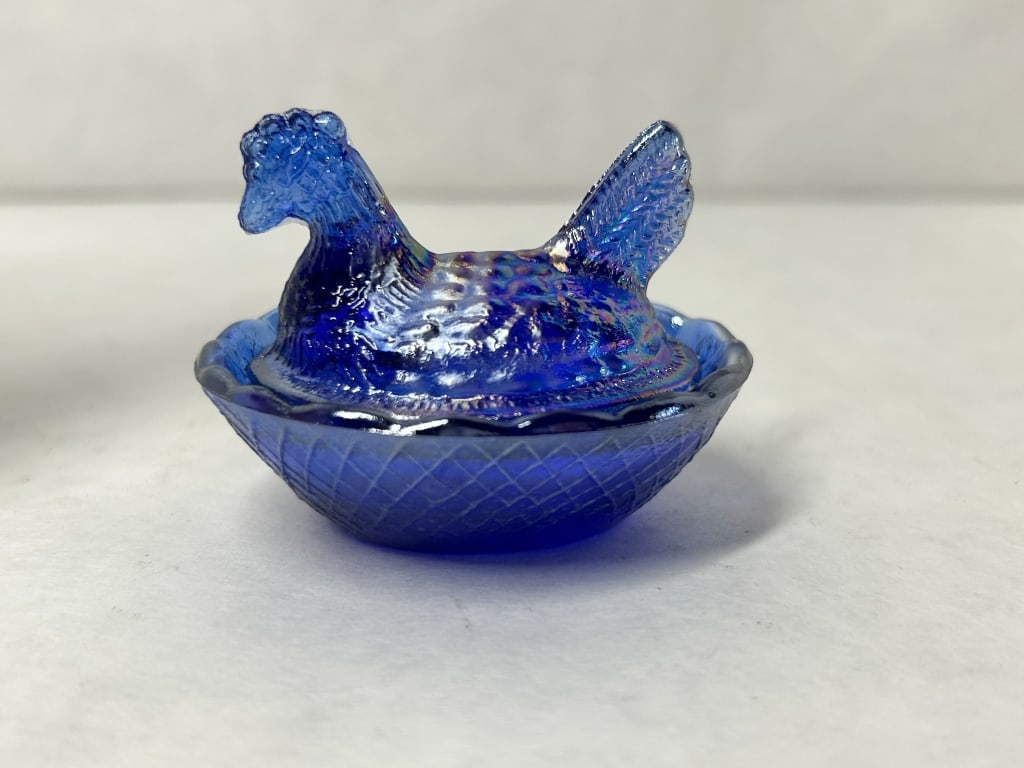 COBALT BLUE IRIDESCENT MINIATURE HEN: A two-piece miniature pressed glass dish in cobalt blue with an iridescent carnival finish. The lid is modeled as a nesting hen atop a base featuring a basket-weave pattern and scalloped rim, with no