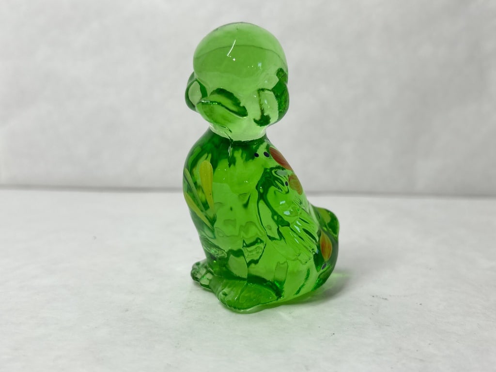 FENTON GREEN GLASS DUCKLING FIGURINE: Hand-painted emerald green glass duckling figurine produced by the Fenton Art Glass Company. A molded mark of a stylized script letter F in an oval is visible on the lower body, and the frosted base f