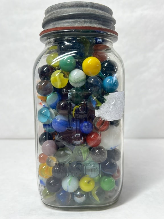 MASON JAR OF VINTAGE GLASS MARBLES: An assortment of over 100 vintage glass marbles presented in a clear glass jar embossed MASON with a zinc lid. The collection includes uranium glass specimens and two white marbles bearing the printed