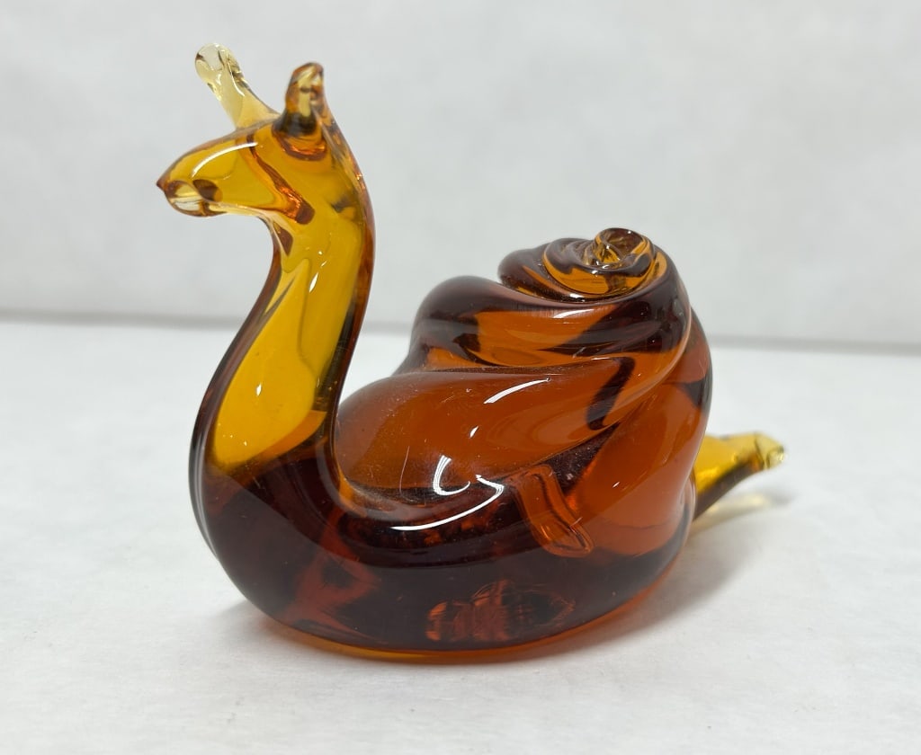MCM AMBER ART GLASS SNAIL, MID-20TH CENTURY: Hand-blown art glass snail figurine featuring a honey-amber body and a shell with deep mahogany color swirls. A rough, unpolished pontil mark is located on the underside of the base, which bears no ma
