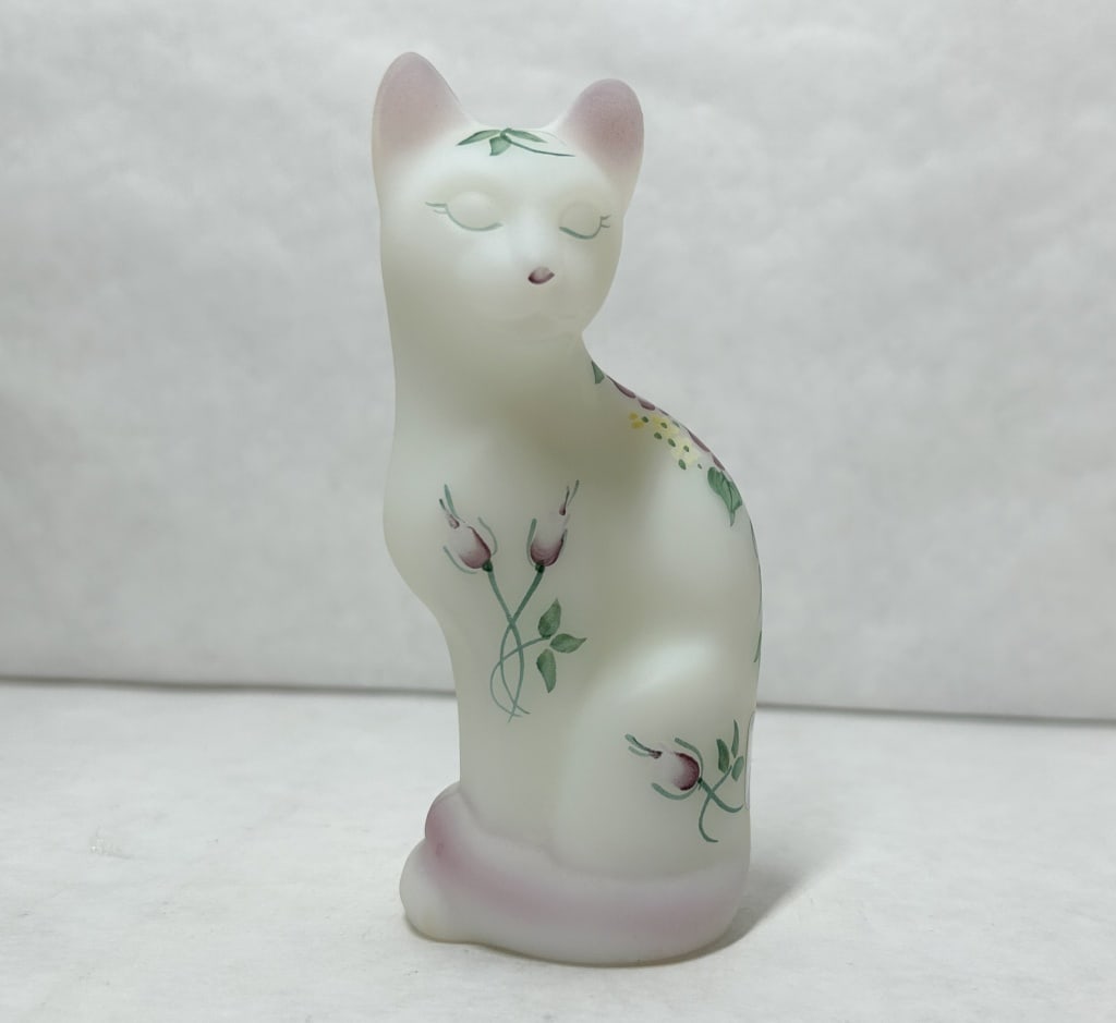 FENTON ROSE GARDEN SATIN GLASS CAT, 2000: Hand-painted opal satin glass stylized cat produced by Fenton Art Glass. A silver 95th-anniversary foil label reading Fenton Art Glass 1905 - 2000 is affixed to the side, and the base features a hand-