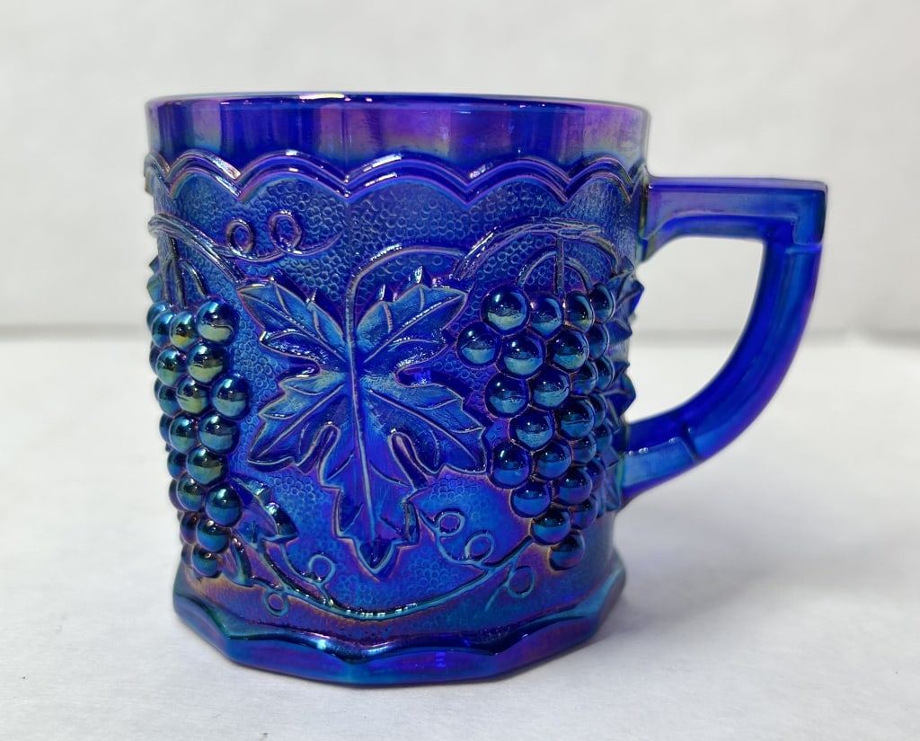 IMPERIAL COBALT CARNIVAL GLASS MUG 1987: Cobalt blue iridescent pressed glass mug produced by the Imperial Glass Company in the Stippled Grape pattern. The interior base is embossed with the IG monogram and the date 1987.