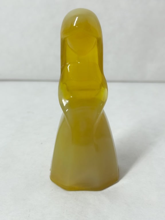 MOSSER AMBER URANIUM SLAG GLASS FIGURINE, 1980S: A modernist figurine of a stylized female figure crafted from amber-yellow slag glass with an integral octagonal faceted base. The translucent body exhibits strong yellowish-green fluorescence under u