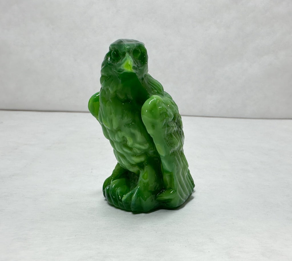 BOYD BERNIE THE EAGLE GREEN SLAG GLASS: A pressed slag glass figurine depicting a perched eagle in a stooping pose with detailed feathering. The object is composed of translucent green glass with opaque white marbling and features an