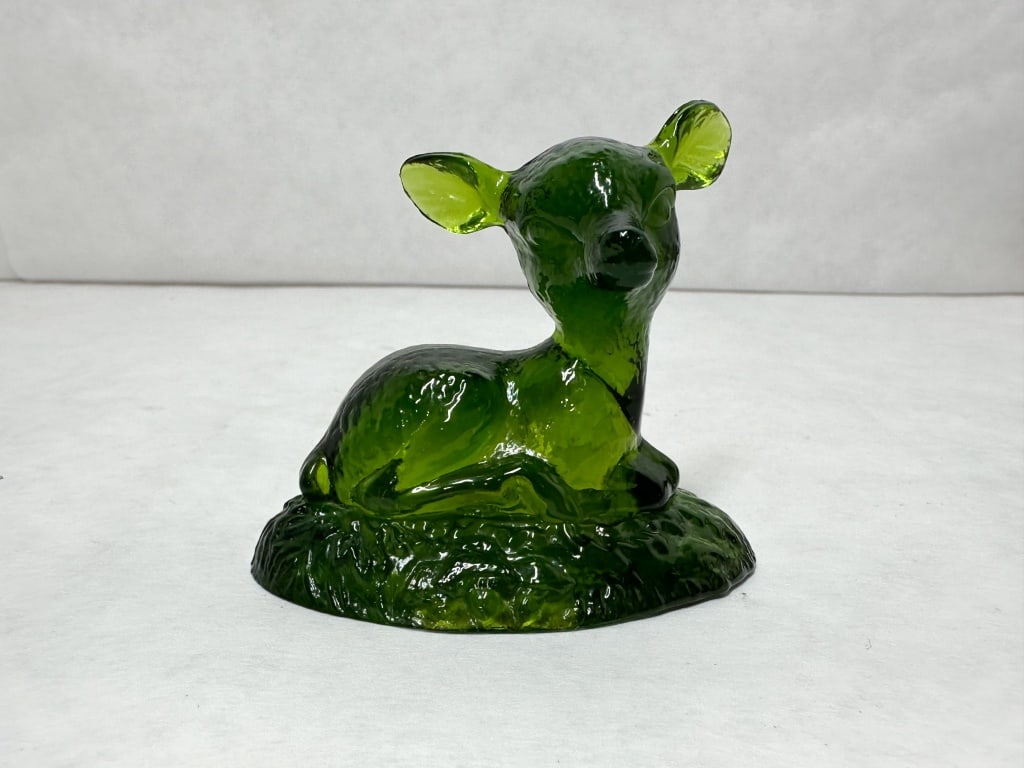BOYD BINGO GREEN GLASS DEER FIGURINE, MID-CENTURY: A forest green pressed glass figurine of a reclining fawn on a textured grass-like base. No maker marks, labels, or signatures are visible on the body or the underside of the base.