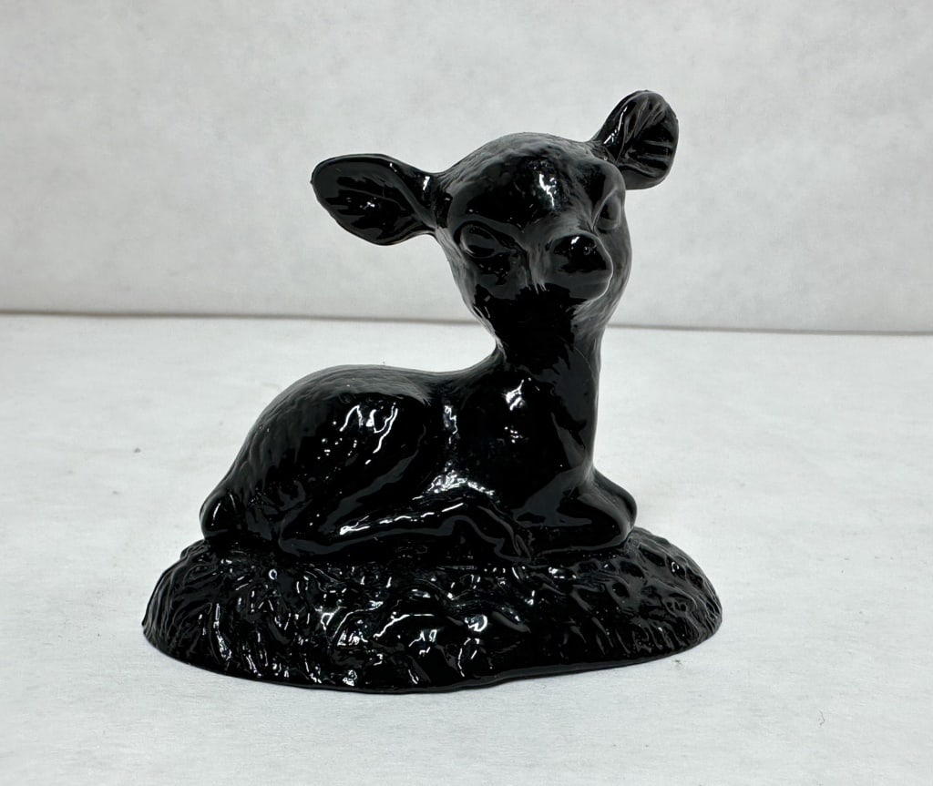 BOYD BLACK BINGO DEER: A mid-century figurine depicting a reclining fawn crafted from high-gloss black glass. The stylized animal is modeled with its head turned back, resting upon a heavily textured integral base.
