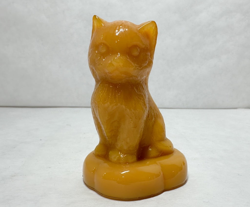 BOYD ORANGE GLASS SITTING KITTEN PILLOW FIGURINE: Opaque orange glass kitten on a pillow figurine produced by Boyd Crystal Art Glass. An impressed mark consisting of a capital letter B within a diamond is visible on the scalloped base.