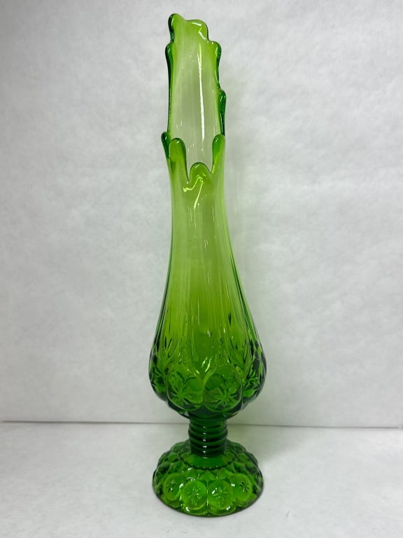 MOON AND STAR GREEN GLASS SWUNG VASE: Mid-century emerald green pressed glass vase in the Moon and Star pattern. The piece features a pedestal base and a hand-stretched swung rim.