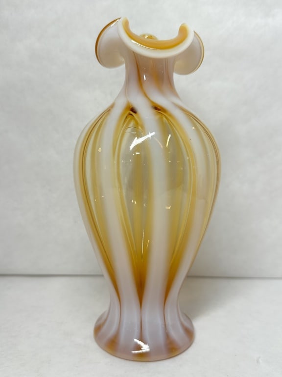 AMBER AND WHITE SWIRL GLASS VASE, MID-CENTURY: A hand-blown art glass vase featuring a vertical optic rib pattern in translucent amber and opaque white. The vessel is designed with a bulbous body and a tri-cornered ruffled rim, and no maker marks 