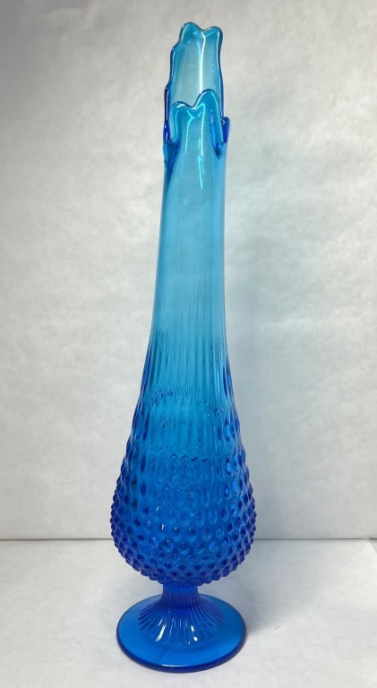 TURQUOISE HOBNAIL GLASS SWUNG VASE, 1960S: Mid-century modern swung glass vase in turquoise blue featuring a molded hobnail pattern. The vessel stands on a pedestal base and features a textured body transitioning into a vertically ribbed neck 