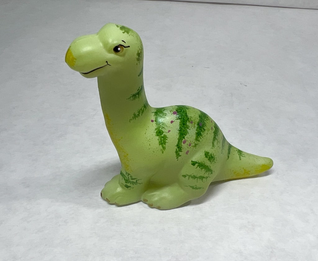 FENTON GREEN STRIPED DINOSAUR: long-necked dinosaur figurine featuring a light green base with dark green vertical stripes and purple spots. The figure is detailed with hand-painted facial features and yellow airbrushed highlights 