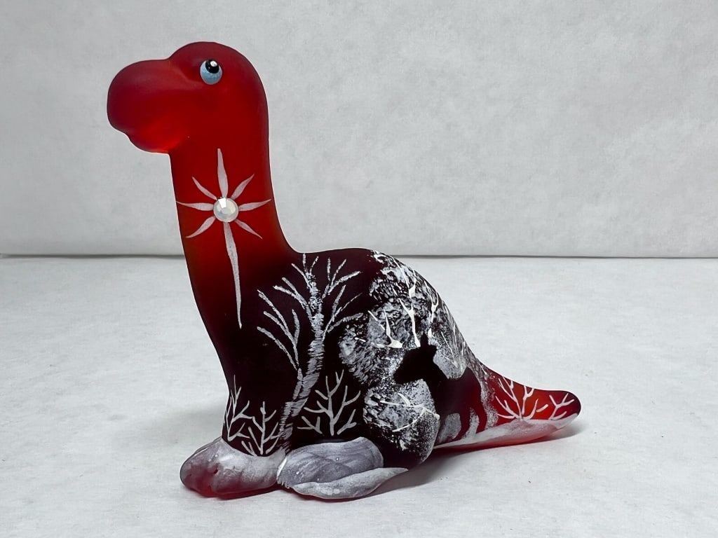 FENTON SATIN GLASS DINOSAUR, 2023: Fenton Gift Shop exclusive dinosaur figurine in ruby-to-ebony satin glass featuring a hand-painted winter scene and starburst with applied rhinestone by J.K. Spindler. The base bears hand-painted mark