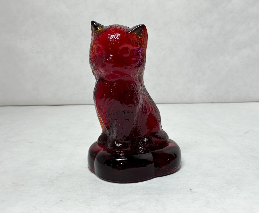 BOYD RUBY GLASS SITTING CAT PILLOW, 1978-1983: A ruby red glass figurine of a seated cat with a textured finish. An embossed mark consisting of the letter B within a diamond is located on the rear base (photo 4), and the glass fluoresces bright or