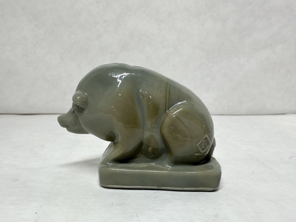 BOYD SUEE THE PIG MARBLED SLAG GLASS: Slag glass pig figurine featuring a marbled grey and olive green color palette with a fire-polished finish. An embossed B within a diamond and a single horizontal underline is visible on the rear flan