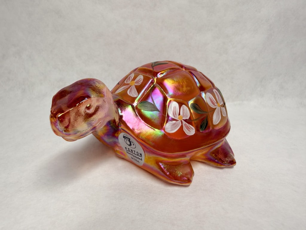 FENTON IRIDESCENT GLASS TURTLE FIGURINE: An American hand-painted iridescent glass turtle figurine produced by the Fenton Art Glass Company for the Yesterday and Today series. The peach-toned piece features floral decoration and carries an o