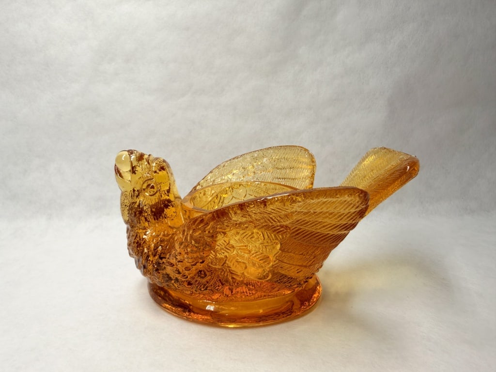 AMBER GLASS BIRD SALT CELLAR, MID-20TH CENTURY: Vintage amber pressed glass salt cellar in the bird and berry pattern. The vessel features molded feather and berry texturing with a central circular well; the underside of the base is smooth and lack