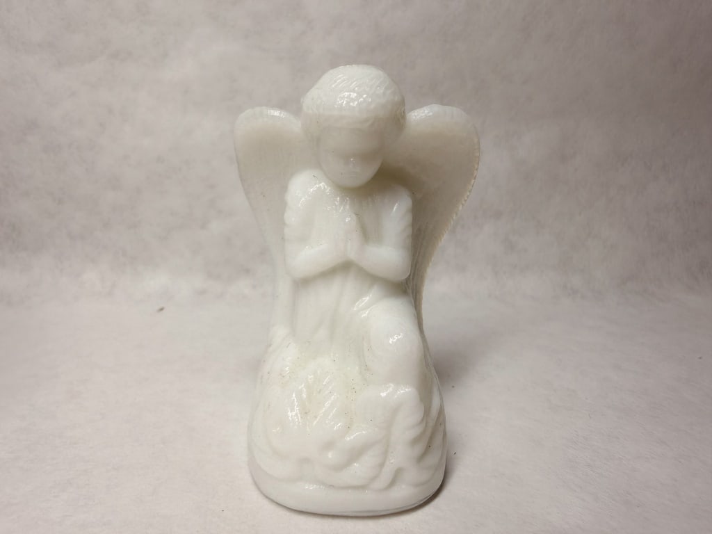 BOYD WHITE MILK GLASS PRAYING ANGEL: A pressed opaque white milk glass figurine depicting a kneeling angel in prayer. The figure features molded wing detailing and a textured base. No maker marks, labels, or stamps are visible on the ext
