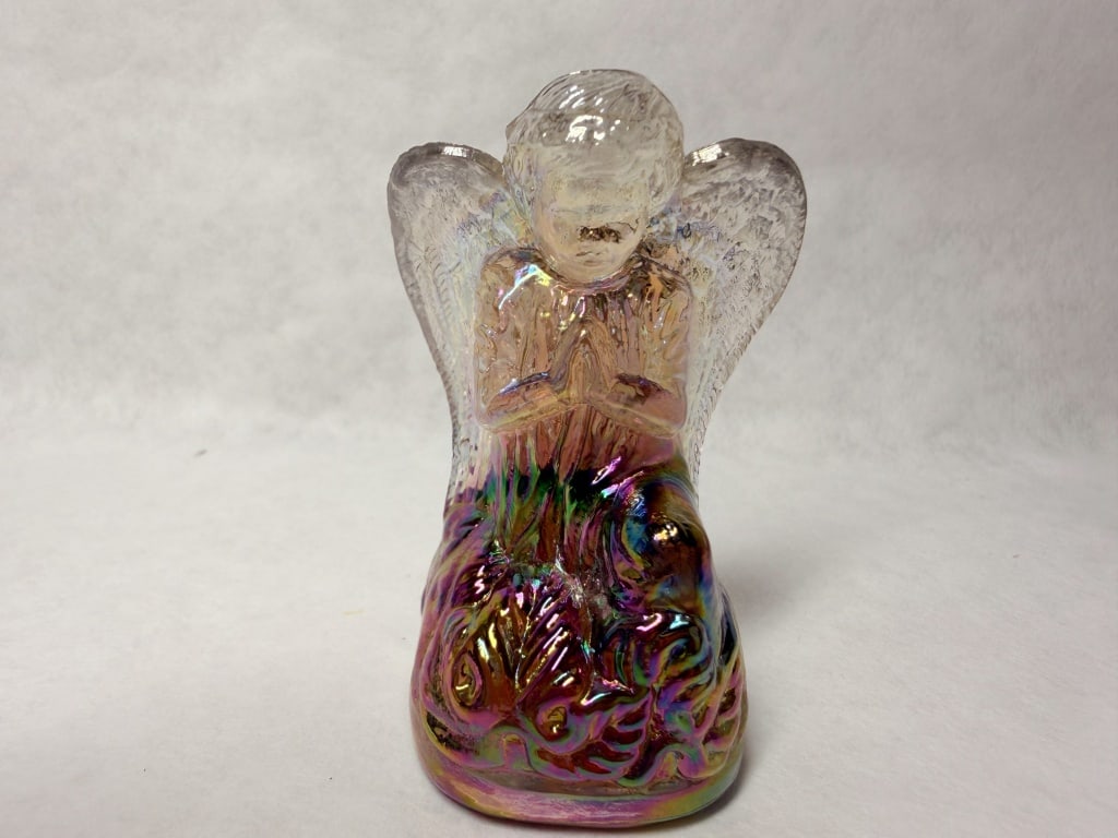 BOYD IRIDESCENT GLASS KNEELING ANGEL FIGURINE: A molded glass figurine of a kneeling angel in prayer featuring a multi-color iridescent finish. The base shows a smooth, concave underside with a central molded swirl that contains no readable charac
