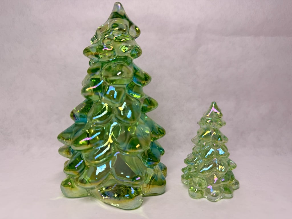 MOSSER PAIR OF IRIDESCENT GREEN GLASS TREES: A pair of molded green art glass Christmas tree figurines featuring a heavy iridescent carnival glass coating. The stylized forms consist of tiered, rounded branch protrusions in two staggered sizes,