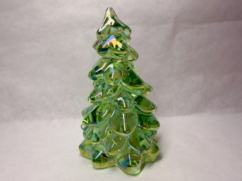 MOSSER IRIDESCENT GREEN GLASS CHRISTMAS TREE: Stylized Christmas tree figurine featuring tiered, rounded boughs tapering to a pointed terminal. The translucent green glass is finished with a vibrant iridescent coating producing rainbow-like