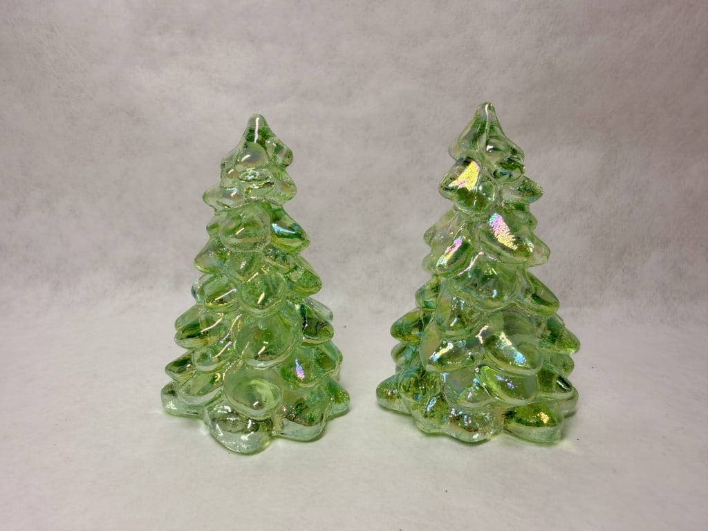 MOSSER MINI PAIR OF CARNIVAL GLASS TREES, CONTEMPORARY: A pair of Mosser Glass Christmas tree figurines in apple green carnival glass. The hand-worked forms feature tiers of rounded, petal-like branches finished with a multicolored iridescent luster coatin
