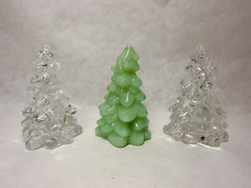 MOSSER MINI TRIO OF GLASS CHRISTMAS TREES: A trio of stylized holiday figurines in the form of Christmas trees, featuring a textured, lobed surface. One tree is composed of semi-opaque jadeite glass, while the remaining two are clear glass.