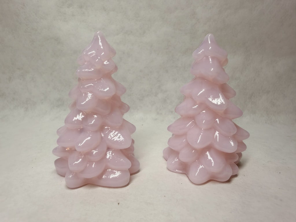 MOSSER MINI PINK CHRISTMAS TREES: A pair of figural evergreen trees crafted from opaque pink glass. Each tree features multiple tiers of ruffled branches with a high-gloss finish.