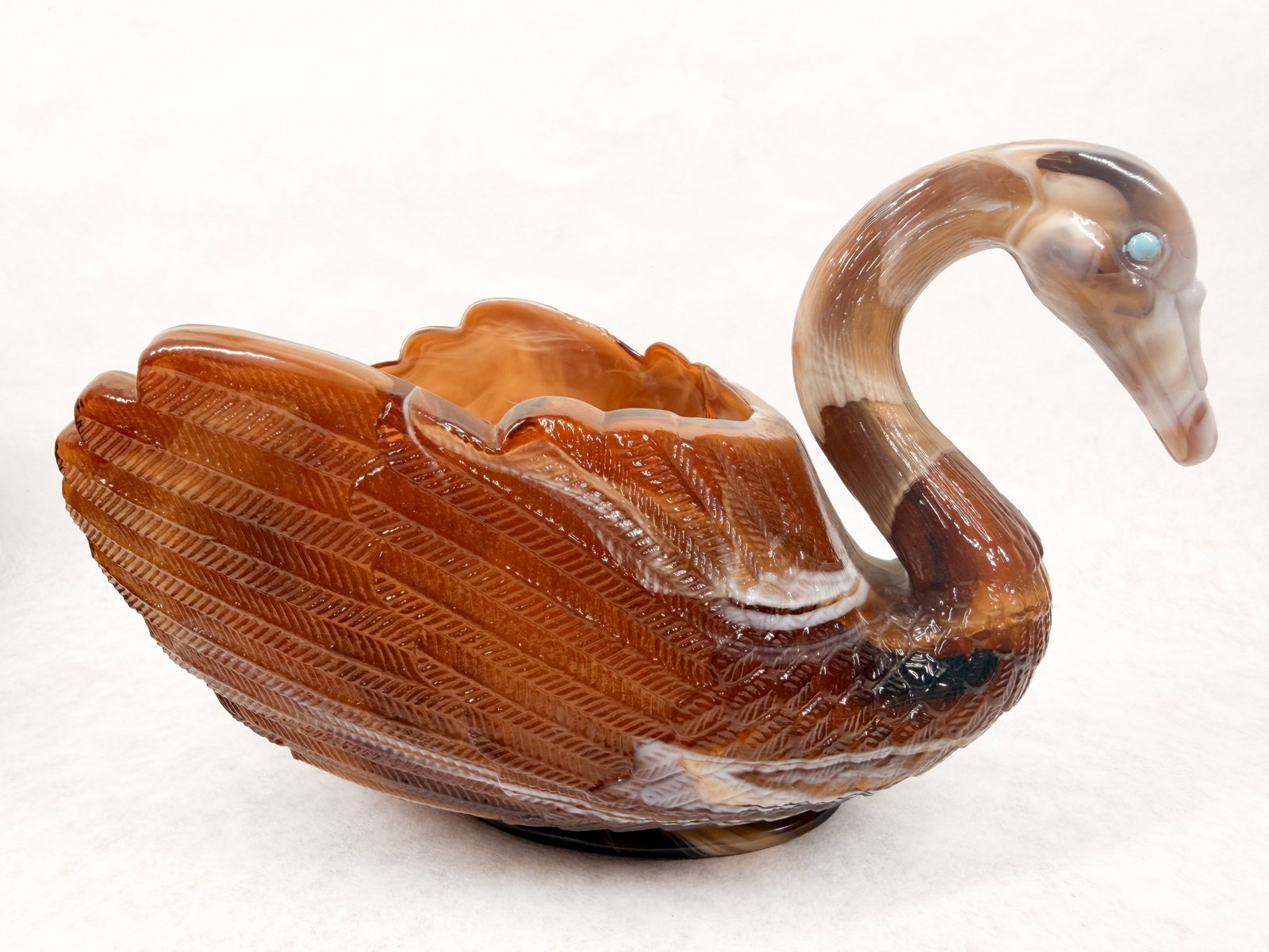 IMPERIAL SLAG GLASS SWAN BOWL, CIRCA 1951-1972: Imperial Glass Corporation caramel slag swan bowl featuring a molded feather pattern and applied blue glass eyes. The underside of the base features an embossed mark consisting of a capital letter I