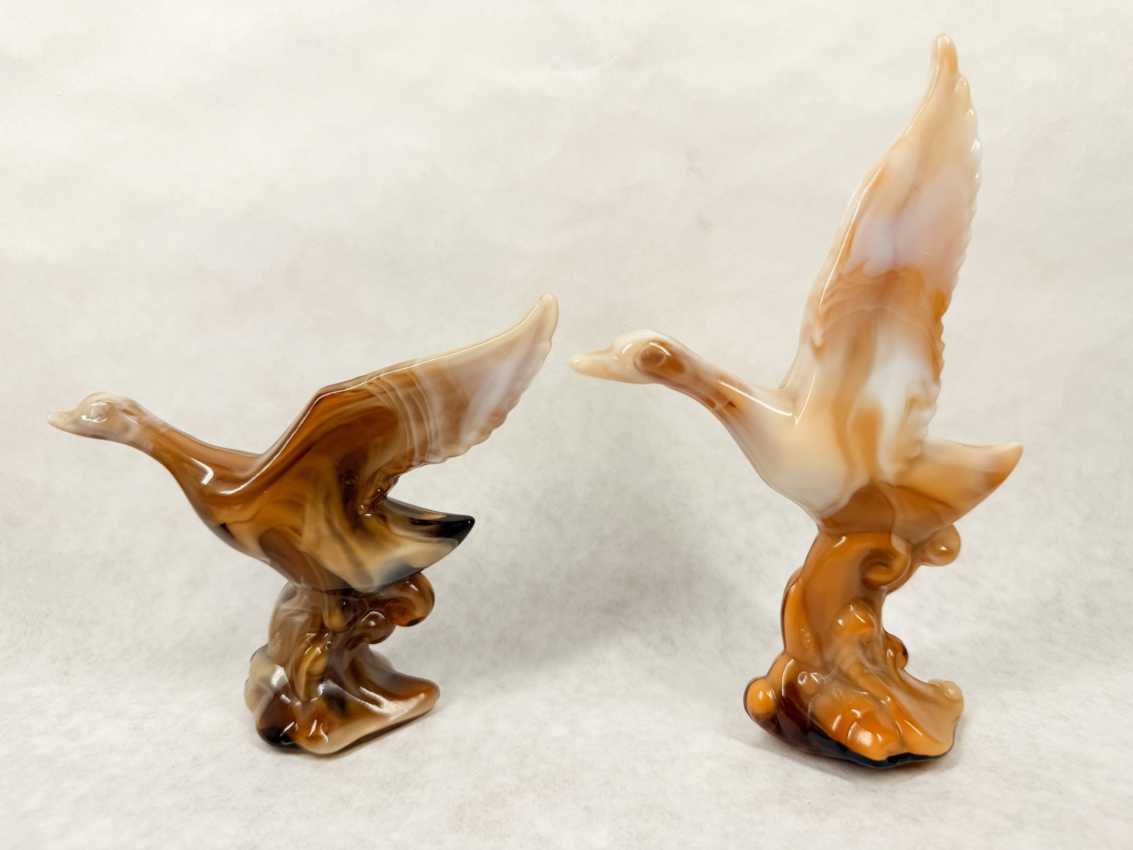 IMPERIAL CARAMEL SLAG MALLARDS 1970S: A pair of caramel slag glass mallard duck figurines in flight produced by the Imperial Glass Company. One base retains a blue foil label reading HAND CRAFTED Imperial USA and a paper label marked