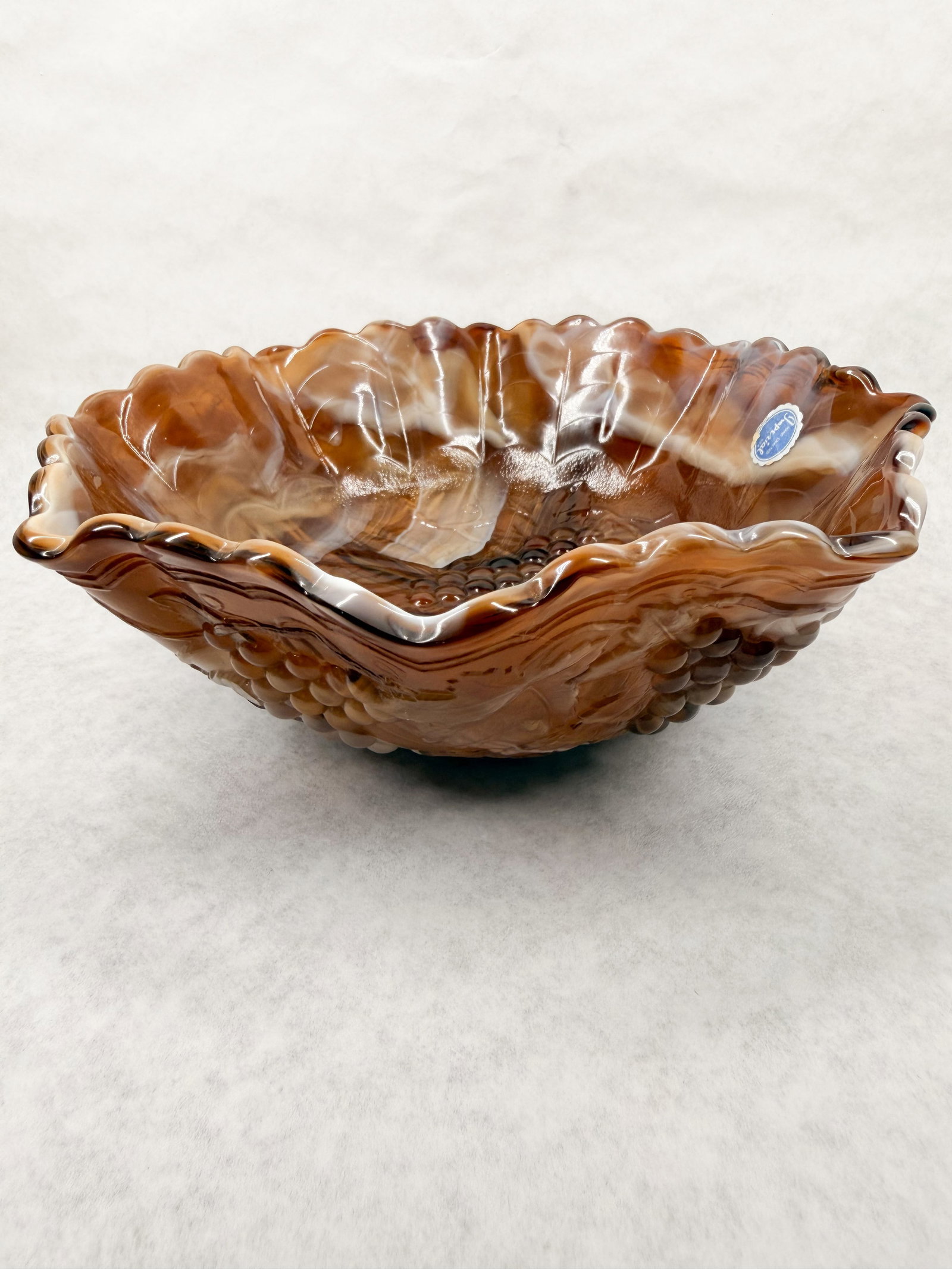 IMPERIAL CARAMEL SLAG GRAPE BOWL VINTAGE: A chocolate slag glass centerpiece bowl produced by the Imperial Glass Company featuring a molded relief grape and leaf pattern with a ruffled rim. The base bears an embossed mark consisting of a
