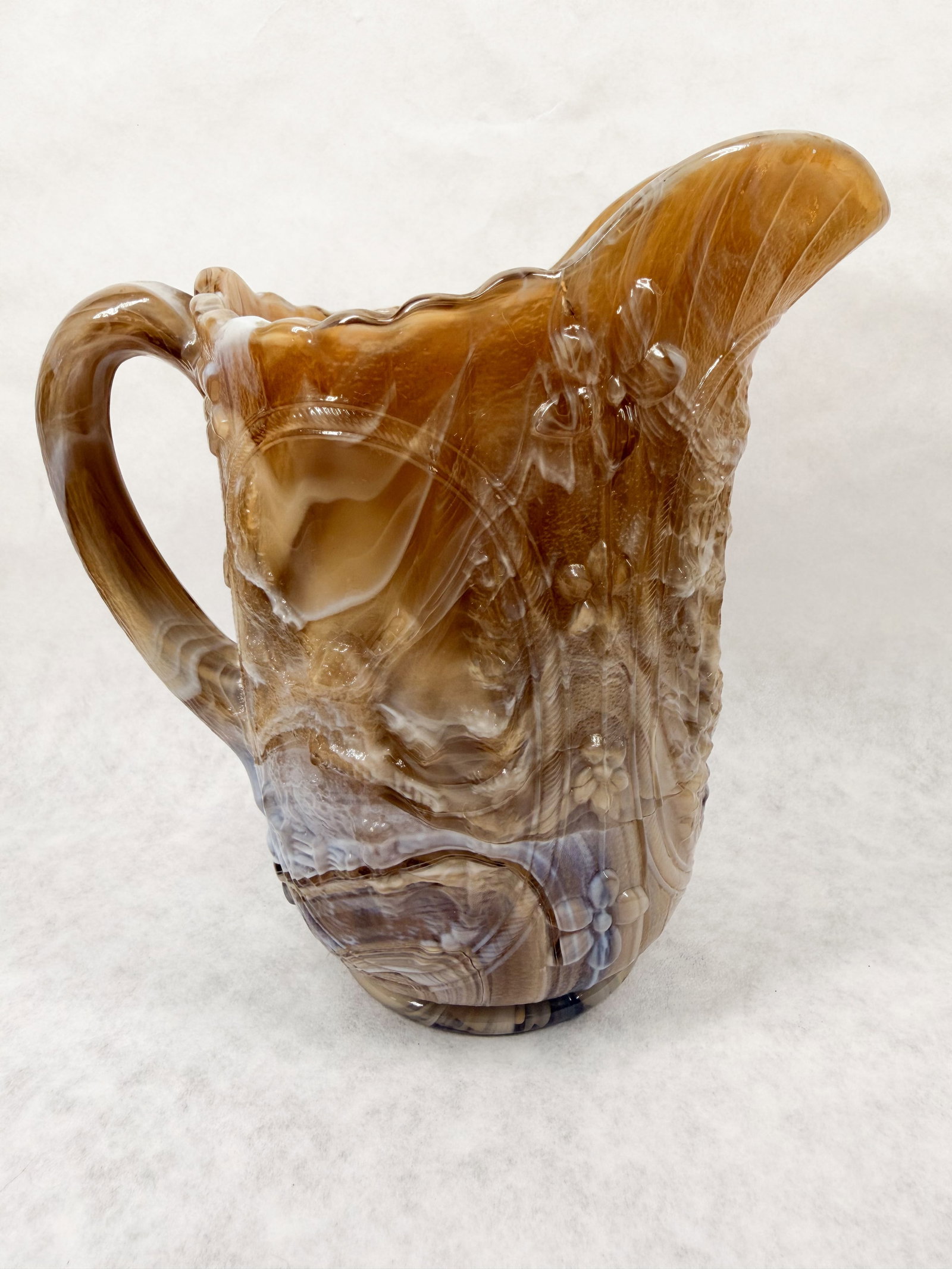 IMPERIAL WINDMILL PATTERN CARAMEL SLAG PITCHER: Pressed glass pitcher in chocolate slag with a molded windmill pattern and scalloped rim. A small white adhesive label on the interior rim is marked with the handwritten number 31.