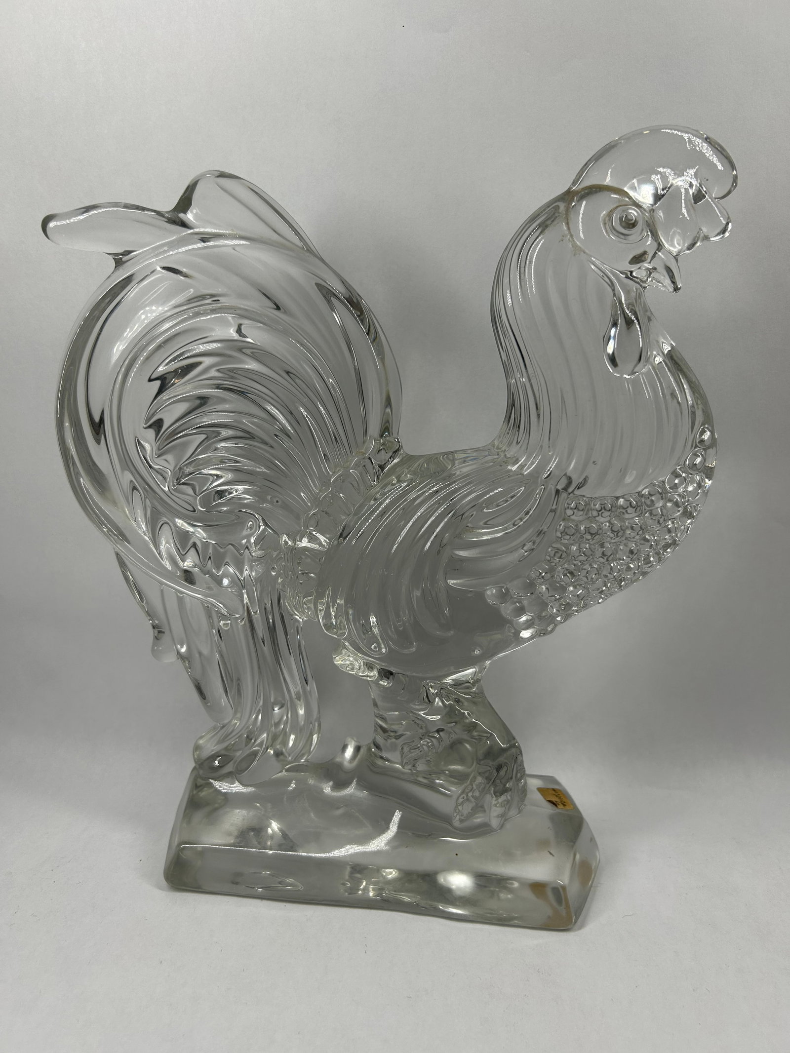 FOSTORIA CLEAR GLASS CHANTICLER ROOSTER: A clear molded glass figurine of a rooster in a crowing posture produced by the Fostoria Glass Company. A rectangular gold foil label is affixed to the base reading "Fostoria" in cursive script.